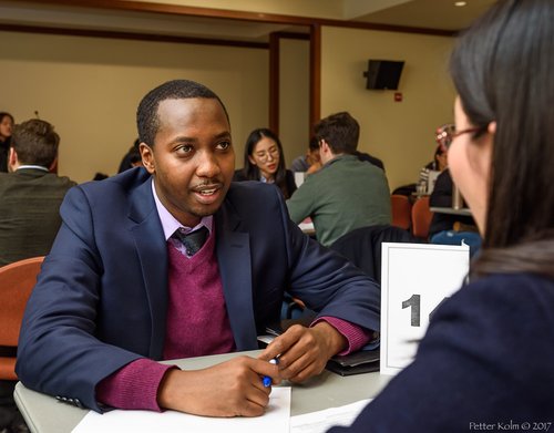 Man in suit with plum-colored sweater doing a mock interview