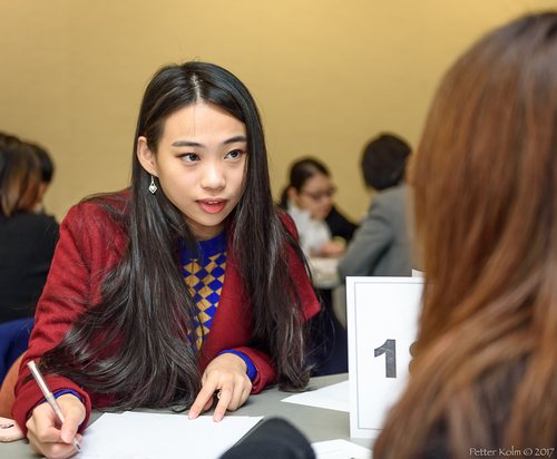 Woman in red coat doing doing a mock interview and writing down notes